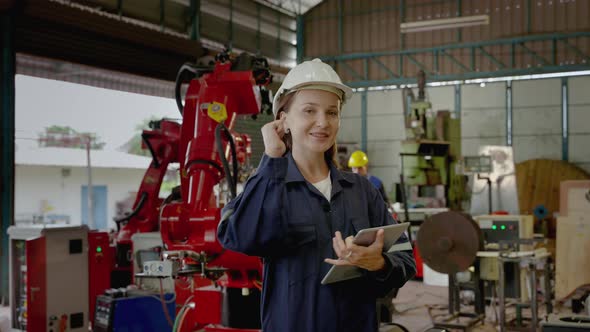 young Caucasian engineer is presenting and explaining how a robotic arm works and thumbs up