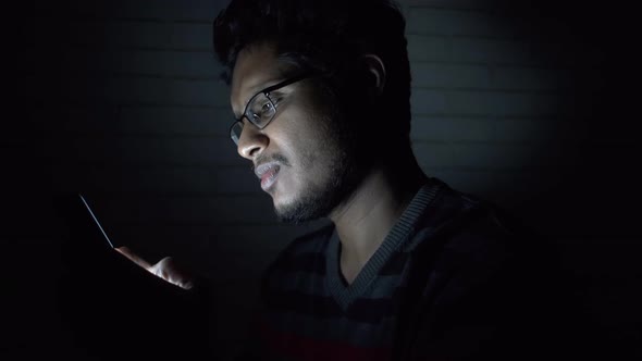 Young Man Sitting on Bed Using Smart Phone at Night