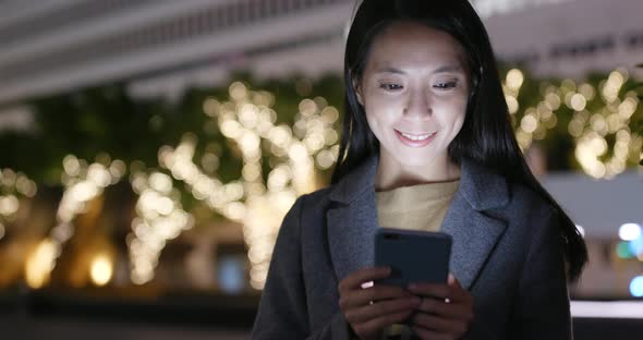 Woman use of smart phone in city at night