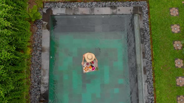 Aerial Shot of a Young Woman Tourist Has Her Own Personal Breakfast on a Floating Table