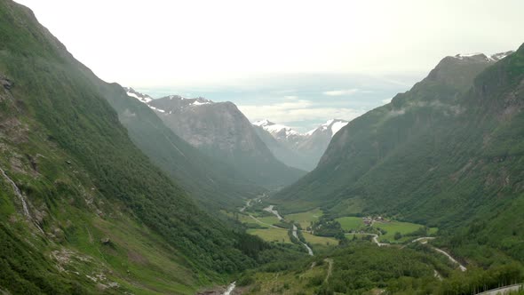 Road Running In Valley Between High Mountains With Snowy Peaks In Stryn, Norway - aerial drone shot