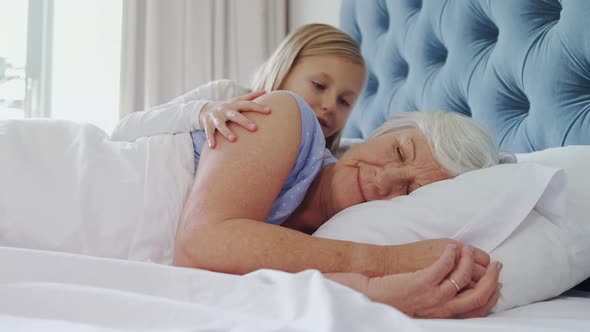 Affectionate granddaughter kissing grandmother in bedroom 4k