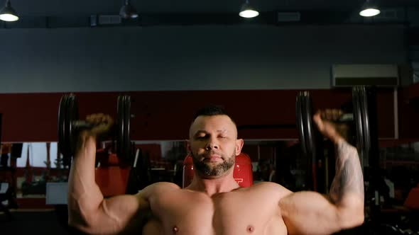 Man with Bare Torso Exercises Dumbbell Raising Up To Head