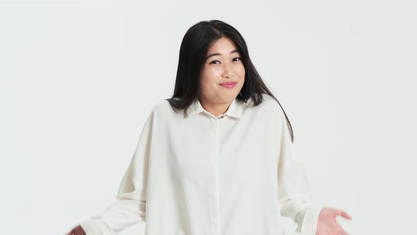 Confused asian korean woman shrugging shoulders