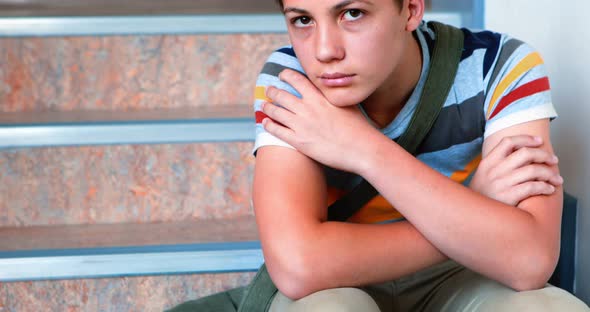 Sad schoolboy sitting alone on staircase