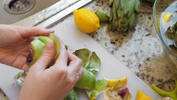 Woman Cleaning Heart of Artichokes with Spoon