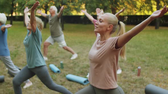 Elderly People Having Outdoor Yoga Workout with Female Instructor