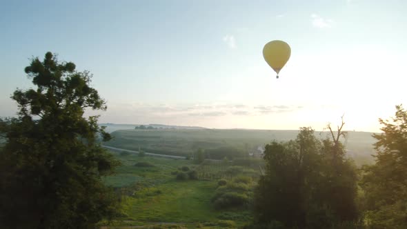 Colorful Hot Air Balloons Fly Over Green Meadows and Morning Fog at Sunrise. Travel, Adventure