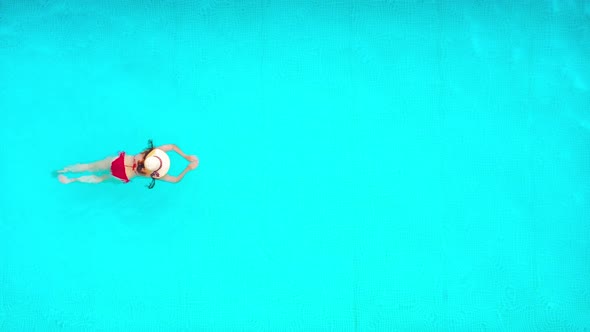 View From the Top As a Woman in Red Swimsuit Swims in the Pool