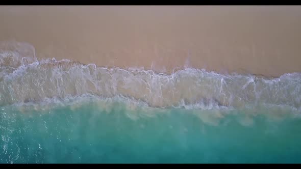 Aerial drone shot landscape of idyllic shore beach vacation by blue green sea with bright sand backg