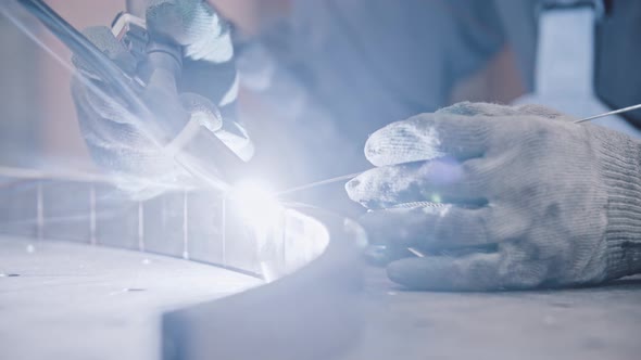 A Worker in Protective Gloves Welding Parts of the Metal Detail Together  Glowing Fire