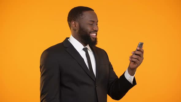 Successful Afro-American Businessman Reading News on Phone, Making Yes Gesture