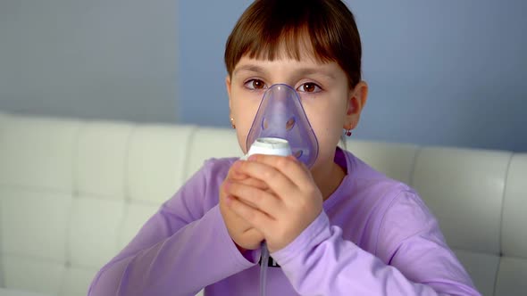 Little Girl Makes Inhalation with Medical Nebulizer While Sitting at Table