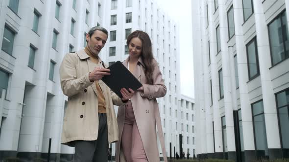 Businessman and businesswoman talking with tablet on street in city Outside Office