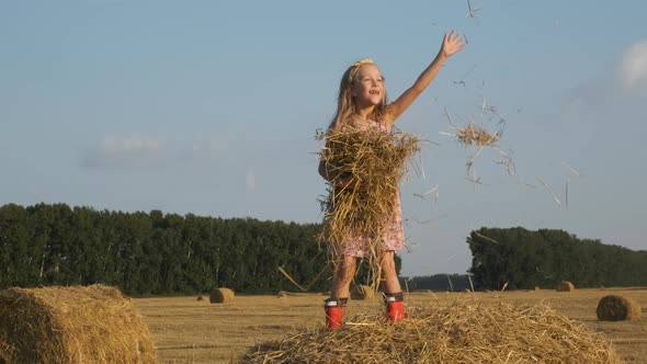 Little Girl Throwing Hay Up in a Harvested Field