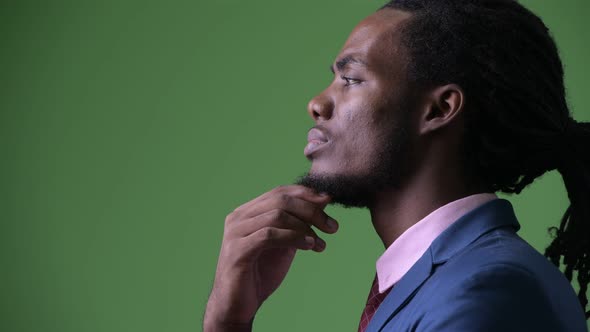 Young Handsome African Businessman with Dreadlocks Against Green Background