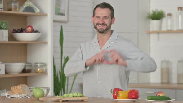 Young Man Making Heart Shape By Hands While in Kitchen