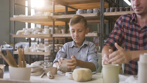 Caring Father Teaching Little Son How to Work with Clay on Potters Wheel