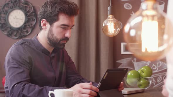 Young Bearded Man Using a Tablet at a Bar Counter