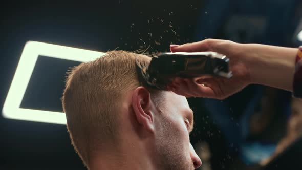 Barbershop: woman hairdresser cuts man's hair with a razor