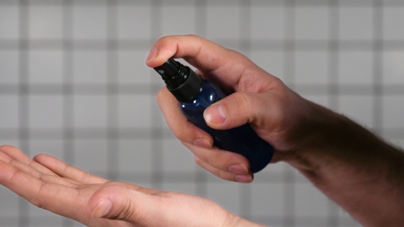 Man dispensing hand sanitizer into hands and sanitizing them.