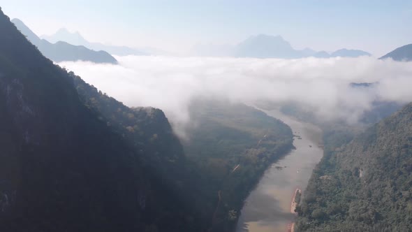 Aerial: drone flying over Nam Ou River in Laos, morning fog mist and clouds, Nong Khiaw Muang Ngoi d