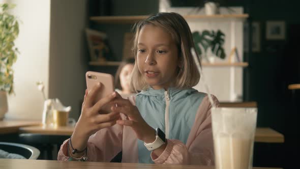 Beautiful Girl in Sitting in Cafe Counter and Drinking Milkshake While Taking Cute Photos