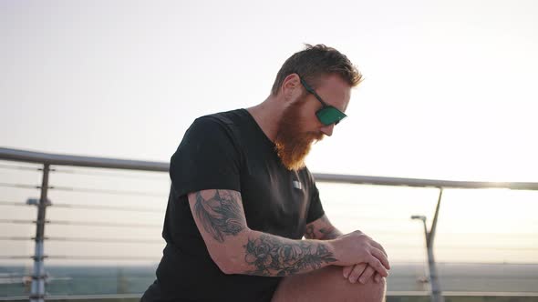 Sportive Man Does Exercise for Legs on Footbridge in City