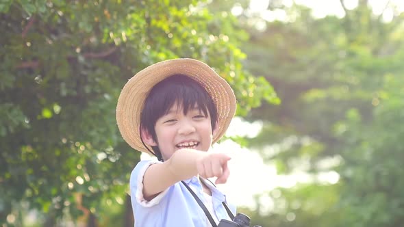 Cute Asian Child Using Binocular And Point To Camera On Summer Day