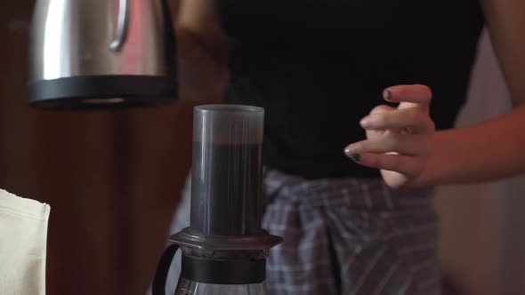 Cafe Worker Pouring Boiling Water From Metal Kettle Into Aeropress to Brew Coffee Close Up in Slow