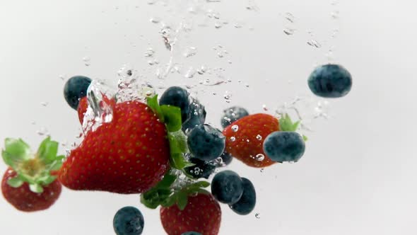 Strawberries And Blueberries Splashing In Cold Water