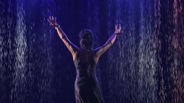 An Attractive Woman in a Wet Dress Performs Elegant Movements with Her Hands in a Dance. A Female