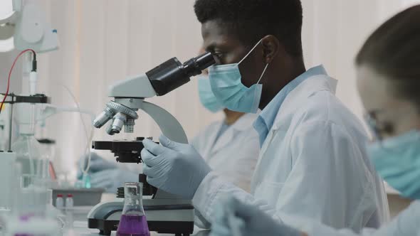 Black Male Scientist in Face Mask Doing Research