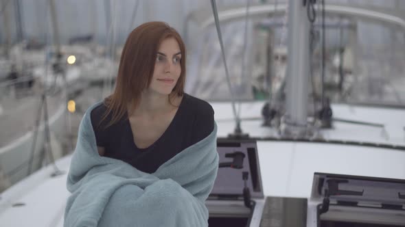 Beautiful Redhaired Woman Sitting in a Plaid on a Yacht in the French Port