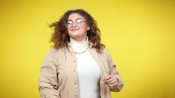 Joyful Charming Overweight Lady Unbinding and Tossing Hair at Yellow Background Smiling