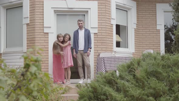 Cute Family Standing on the Porch Together. Mother and Father Kissing Goodbye To Little Daughter and