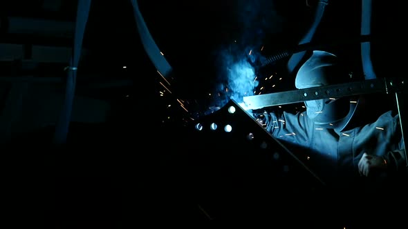 View of Man in Plant Workshop Welding with Torch