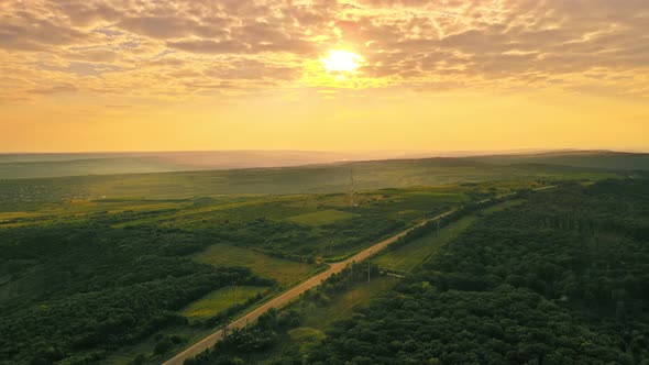 Aerial drone view of nature in Moldova at sunset. Highway, wide fields and hills, forest