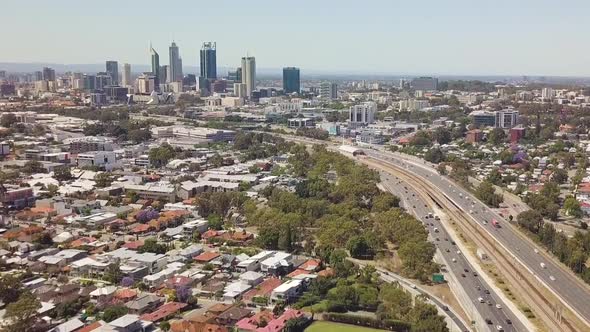 Aerial, busy freeway leading into distant highrise city. Perth, Australia.