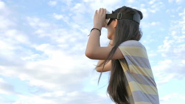 Slow motion 4K of Asian girl having fun with virtual reality glasses while standing over the sky.