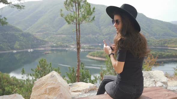 Traveler Woman Sitting on Wooden Bench and Watching Mountain Lake