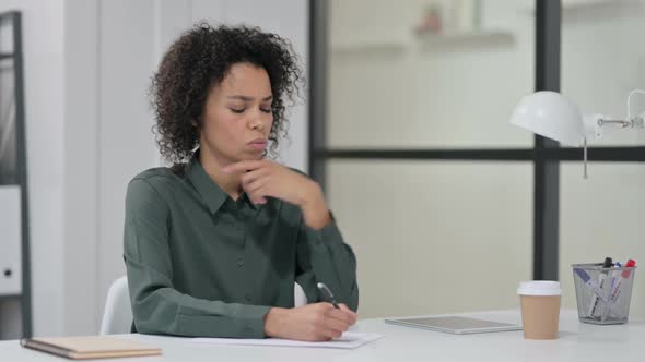 African Woman Writing on Paper at Work