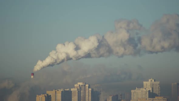 City Pipes Emit Steam Into the Atmosphere Against the City Skyline 9