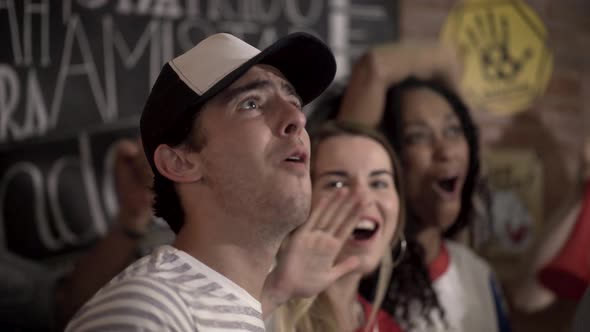 Football fans bonding while watching televised match at sports bar