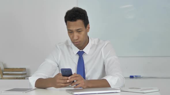 AfroAmerican Businessman Using Smartphone for Online Work