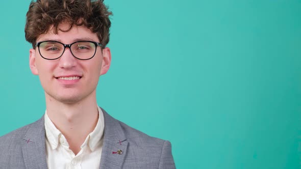 Curly Haired Handsome Young Man That is Putting on Eye Glasses and Smiling