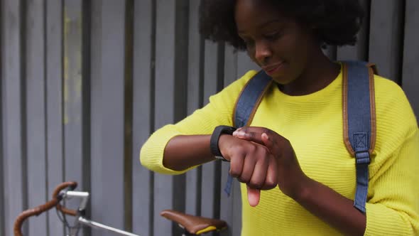 African american woman looking at smartwatch in street