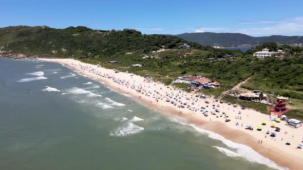 Aerial drone view of tropical tourist beach with people enjoying the sea and the sand umbrella on th