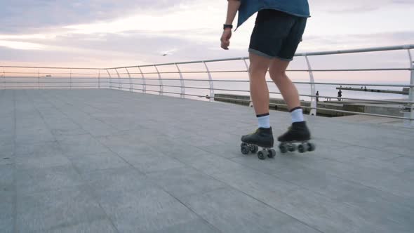 a Young Caucasian Man Roller Skating with Quad Skates Near the Sea Slow Motion