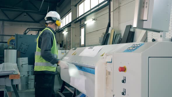 Male Employee Is Operating a Machine Processing a Metal Sheet